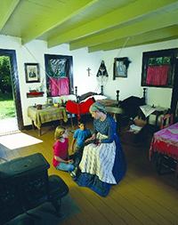 Intérieur d'une vieille maison avec une interprète féminine en costume d'époque montrant une écharpe métisse à deux enfants.